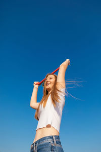 Low angle view of woman against blue sky