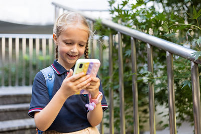 Happy girl using mobile phone outdoors