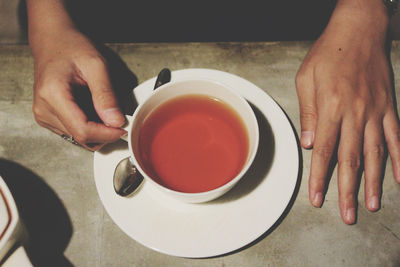 Midsection of woman holding coffee cup on table