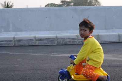 Cute boy sitting on toy car