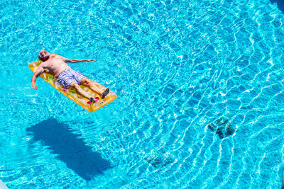 High angle view of man relaxing in swimming pool