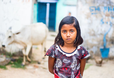 Portrait of girl standing against house