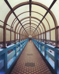 Rear view of people walking in covered bridge