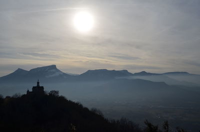 Sun shining through clouds over mountain