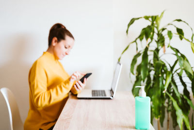 Young woman using smart phone while sitting on table