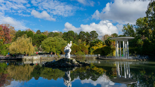 Statue by lake against sky
