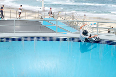People swimming in pool by sea