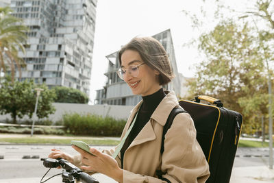Portrait of smiling young woman holding umbrella in city