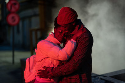 Young happy romantic african couple in love hugging outdoors at night, standing on empty dark street