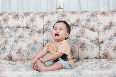 Cute baby girl sitting on bed