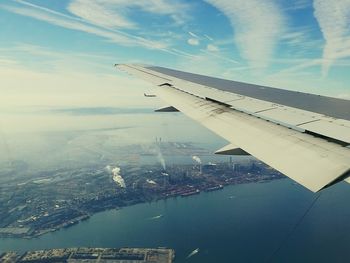 Aerial view of airplane flying over sea against sky