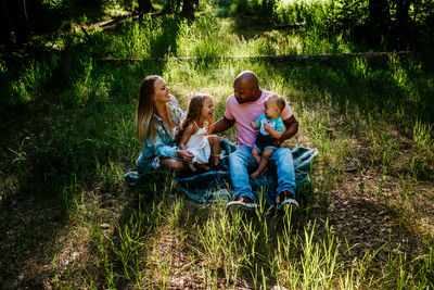 Young family laughing and giggling while sitting on the ground outside