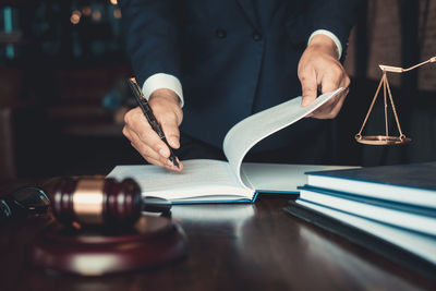 Midsection of man reading book on table