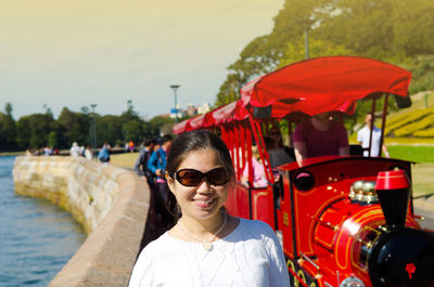 Portrait of smiling mature woman wearing sunglasses standing in park