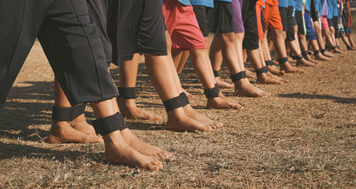 Low section of people playing three legged race on field