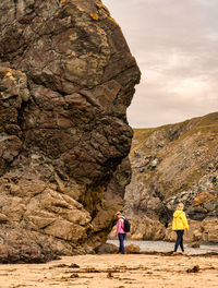 Rear view of people on rock formation against sky