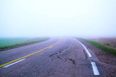 Surface level of empty road against foggy sky