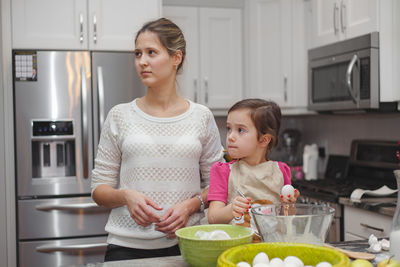 Cute girl with mother preparing food in kitchen