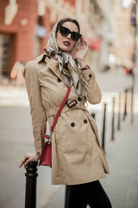 Portrait of fashionable woman in sunglasses standing against building in city