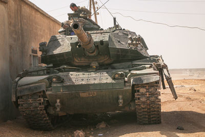 Man in armor tank on land against sky