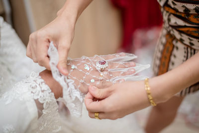 Midsection of bridesmaid adjusting bride glove