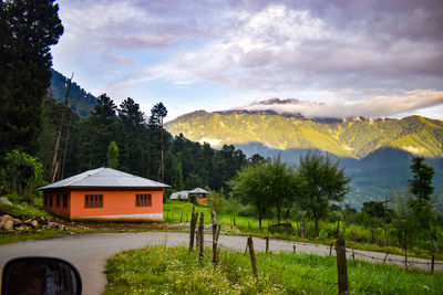 House by trees and mountains against sky