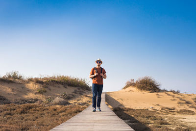 Full length of man standing on road against clear sky