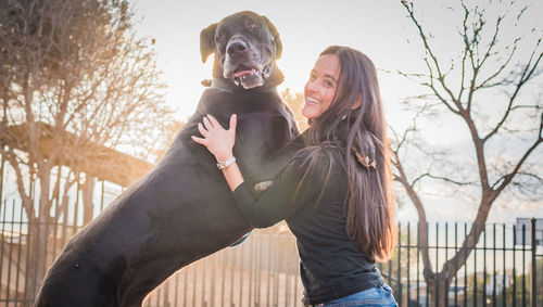 Smiling woman embracing dog against sky