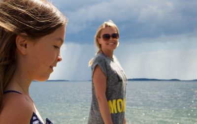 Mother and daughter at beach against sky