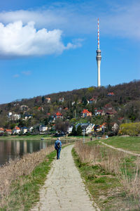 People on walkway amidst buildings in city against sky