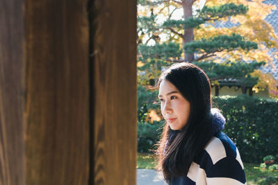 Thoughtful woman by wood against trees