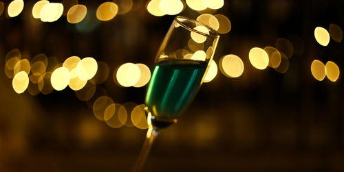 Close-up of wine glass against illuminated lights