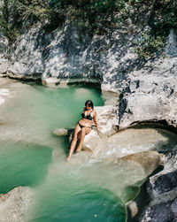 Young woman in bikini sitting on rock by river. summer, lifestyle, vacation.