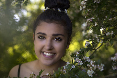 Portrait of smiling young woman against plants and trees