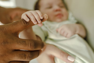 Baby girl holding finger of father at home