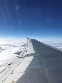 Airplane wing over clouds against blue sky