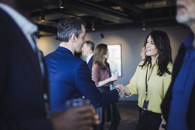 Male entrepreneur shaking hands with female colleague while standing in office