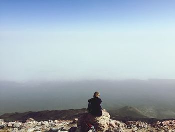 Rear view of woman photographing on landscape against sky