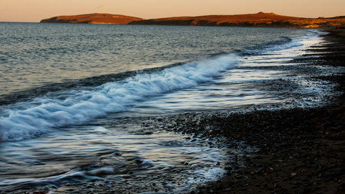Waves rushing towards shore at sunset