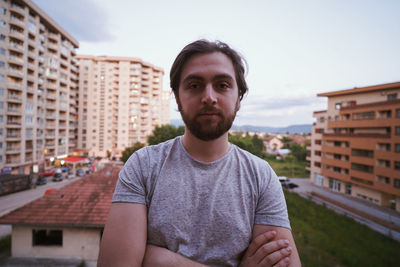 Portrait of young man standing against buildings