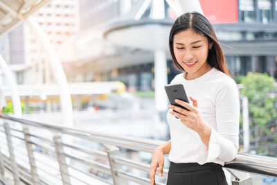 Mid adult woman using mobile phone in city