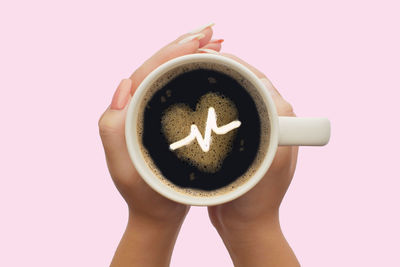 Close-up of hand holding coffee cup against white background