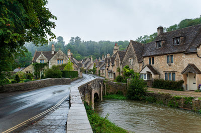 Houses by river amidst buildings against sky