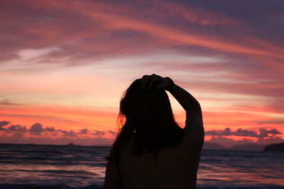 Silhouette woman against sea during sunset