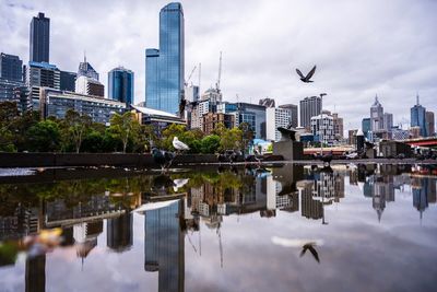 Reflection of buildings in city against sky