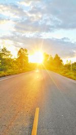 Road amidst trees against sky during sunset