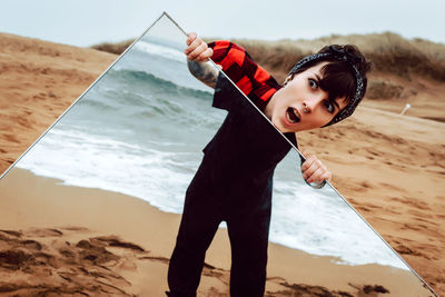 Portrait of boy holding umbrella on beach