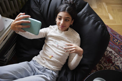 Girl lying on bean bag and taking selfie