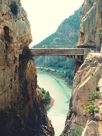 Bridge over river amidst rocky mountains at caminito del rey