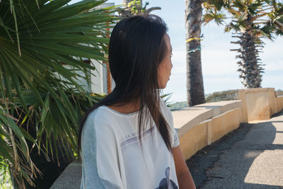 Rear view of woman standing on palm tree